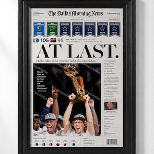 May include: A framed newspaper front page titled The Dallas Morning News, dated June 13, 2011, featuring the headline AT LAST. The print displays the Dallas Mavericks NBA championship victory, including a photograph of players holding the trophy.