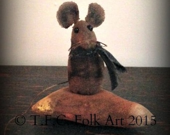 May include: A brown felt mouse with black button eyes and a black felt scarf is standing on a brown felt base. The base has a gold accent and the text "T.F.C. Folk Art 2015" is printed on the base.