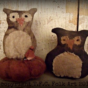 May include: Two handmade fabric owls, one brown and one black, with burlap accents. The brown owl is sitting on a red pumpkin. The owls have a primitive folk art style. Copyright T.F.C. Folk Art 2012.