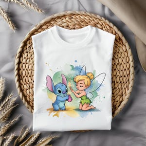 May include: A white t-shirt with a blue and green cartoon image of Stitch and Tinkerbell. Stitch is holding a pink jar and Tinkerbell is sprinkling fairy dust.