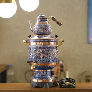 May include: A blue and copper electric samovar with intricate floral designs. The samovar has a teapot on top and a spigot on the side.