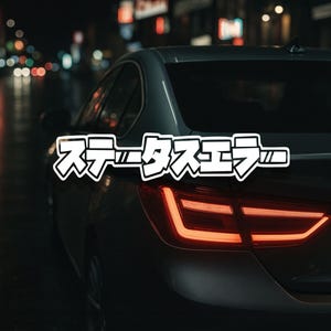 May include: A dark grey car with bright red taillights is shown at night. The Japanese text "ステータスエラー" is displayed in a white outlined font across the car's rear. The background is blurred with city lights.