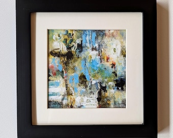 May include: Abstract painting in a black frame with a white mat. The artwork features a colorful mix of blue, green, yellow, red, and black brushstrokes. The painting is square and mounted on a white wall.
