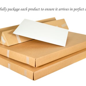 May include: Two flat rectangular cardboard boxes and two triangular cardboard tubes stacked together, with a white rectangular card placed on top. The text "We carefully package each product to ensure it arrives in perfect condition." is visible.
