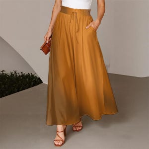 May include: A pair of mustard yellow wide-leg trousers featuring a high-waisted design with an elasticated, gathered waistband and a matching drawstring tie. The trousers have a loose, flowing silhouette that extends to the ankles and includes side pockets.