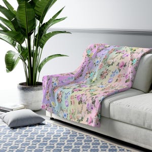 May include: A soft, plush throw blanket with a pastel rainbow ombre background and a floral pattern featuring pink, blue, and yellow roses.