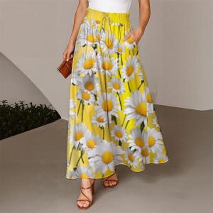 May include: A floor-length yellow skirt featuring a repeating white daisy print with a yellow center. The skirt has a high-waisted design with an elasticized waistband, a drawstring tie, and side pockets, falling in a loose, flowing silhouette.