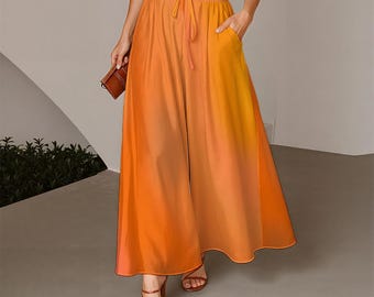 May include: A high-waisted, wide-leg skirt in a vibrant orange ombre gradient that transitions from a lighter yellow-orange at the waistband to a deep, saturated orange at the hem. It features an elasticized waist with a matching drawstring.