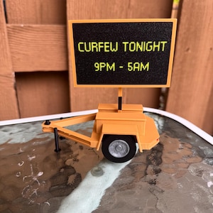 Può includere: Un rimorchio giocattolo giallo con un cartello nero che recita "CURFEW TONIGHT 9PM - 5AM".