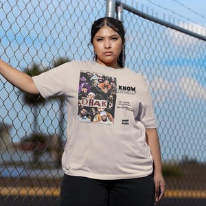 May include: A beige t-shirt with a graphic print of a group of people, including Drake, with the text "KNOW YOURSELF" printed on the front.