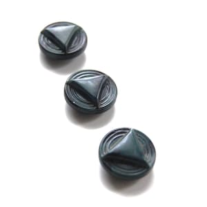 May include: Three dark green buttons with a raised triangular design. The buttons have a concentric circle pattern around the triangle.
