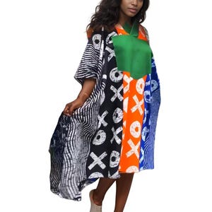 Peut inclure: Une robe colorée à motifs avec un décolleté vert et une variété de motifs. La robe présente des rayures noires et blanches, du noir avec XOXO blanc, de l'orange avec XOXO blanc et du bleu avec des rayures blanches. La modèle porte des baskets blanches.