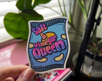 Könnte beinhalten: Ein blauer und weißer Aufkleber mit einem Chipstüten-Design. Der Text auf dem Aufkleber lautet "Salt & vinegar queen" in einem rosa und violetten Farbverlauf.