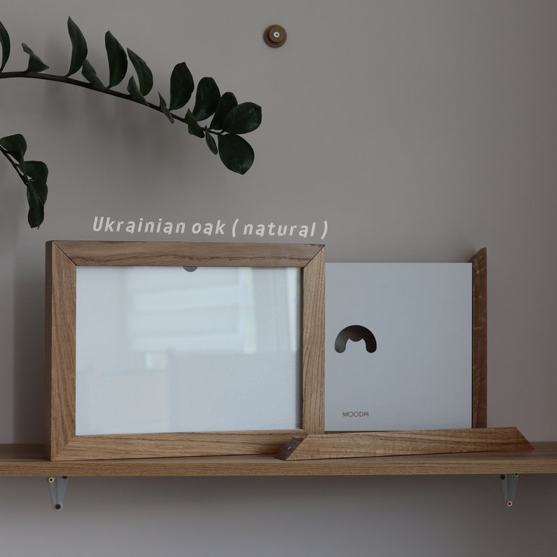 May include: A natural wood picture frame made from Ukrainian oak. The frame is on a shelf with a white background.