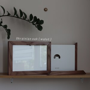 May include: A wooden picture frame with a white mat and a white background. The frame is made of Ukrainian oak (walnut).