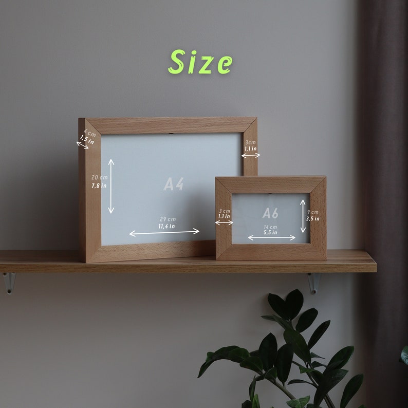 May include: Two wooden picture frames, one labeled "A4" and the other "A6", with measurements in inches and centimeters. The frames are on a wooden shelf.