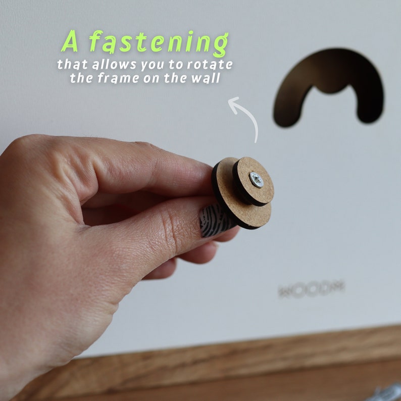 May include: A close-up of a wooden fastening system with a screw. The fastening system is designed to allow a frame to rotate on a wall.