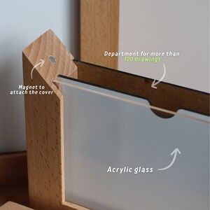 May include: A wooden picture frame with a clear acrylic glass front. The frame has a compartment for storing more than 100 drawings. A magnet is used to attach the cover.