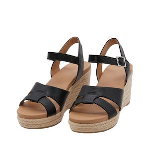 Op de afbeelding: Zwarte leren wedgesandalen met een geweven jute platform en enkelband. De sandalen hebben een kruislings ontwerp aan de voorkant.
