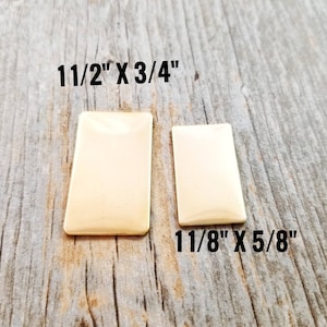 May include: Two rectangular brass plates on a wooden surface. The larger plate measures 1 1/2 inches by 3/4 inches. The smaller plate measures 1 1/8 inches by 5/8 inches.