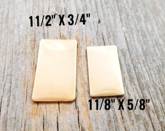 May include: Two rectangular brass plates on a wooden surface. The larger plate measures 1 1/2 inches by 3/4 inches. The smaller plate measures 1 1/8 inches by 5/8 inches.