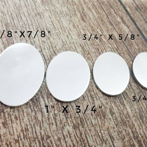 Può includere: Cinque dischi di metallo argentato di dimensioni diverse, con misure in pollici. I dischi sono disposti in una fila dal più grande al più piccolo. Le misure sono: 1 1/8" x 7/8", 1" x 3/4", 3/4" x 5/8", 3/4" x 1/2".