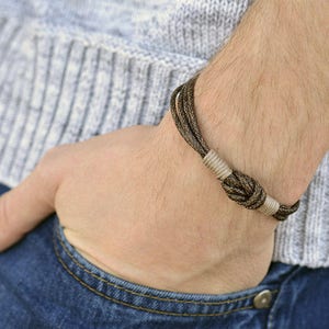 May include: A brown and beige braided bracelet with a knot detail.