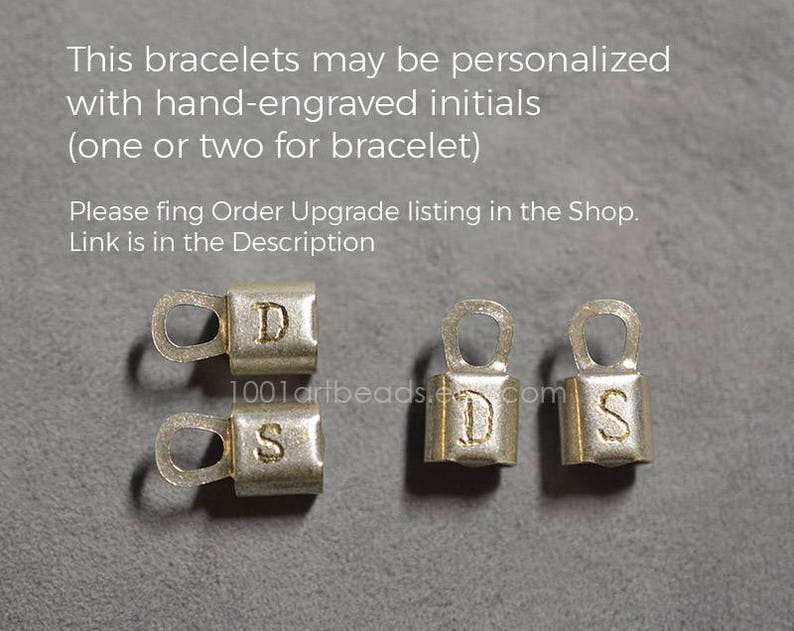 May include: Four silver metal clasps with engraved letters D, S, D, and S. The clasps are used for jewelry making.