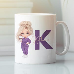 May include: White ceramic mug featuring a cartoon illustration of a blonde woman in purple medical scrubs holding a coffee cup. The mug has a purple letter K and the name Katherine in gold lettering.