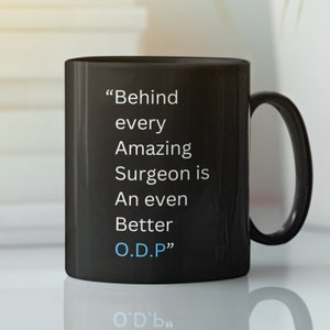 May include: Black coffee mug with white text that reads "Behind every Amazing Surgeon is An even Better O.D.P."
