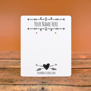 May include: White card with black text and graphics. The text reads "Your Name Here" and "Your Website Here.com". The graphics include a diamond, arrows, and a heart.