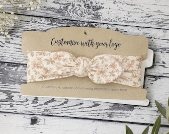 May include: A beige fabric headband with a floral pattern featuring small light brown flowers and leaves, displayed on a rectangular kraft paper card with the printed text Customize with your logo and Custom text, website, social media information down here.