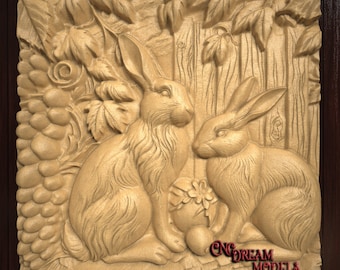 May include: A wooden carving of two rabbits sitting next to each other. The rabbits are surrounded by leaves and grapes. The carving is painted in a light brown color. The text "CNC DREAM MODELS" is visible at the bottom of the carving.