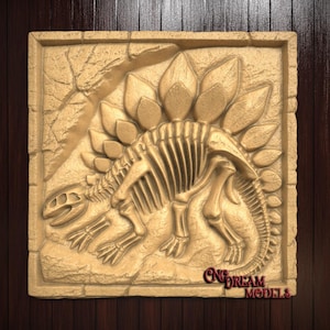 May include: A detailed relief carving of a Stegosaurus skeleton in a square frame. The artwork is in a light tan color, with the dinosaur's bony structure and plates clearly defined. The background has a textured, rocky appearance. The text "CNCDREAM MODELS" is visible.
