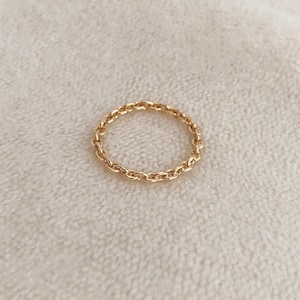 May include: A gold chain ring with a delicate design. The ring is simple and elegant, perfect for everyday wear.