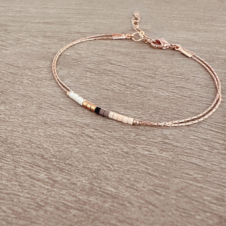 May include: A delicate double-strand bracelet with a small row of white, black, and brown beads.