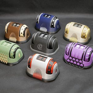 May include: Seven different colored counter devices with rotating number wheels. Each device has a different color and design. The numbers on the wheels are 12, 39, 24, 28, 71, 17, and 45.