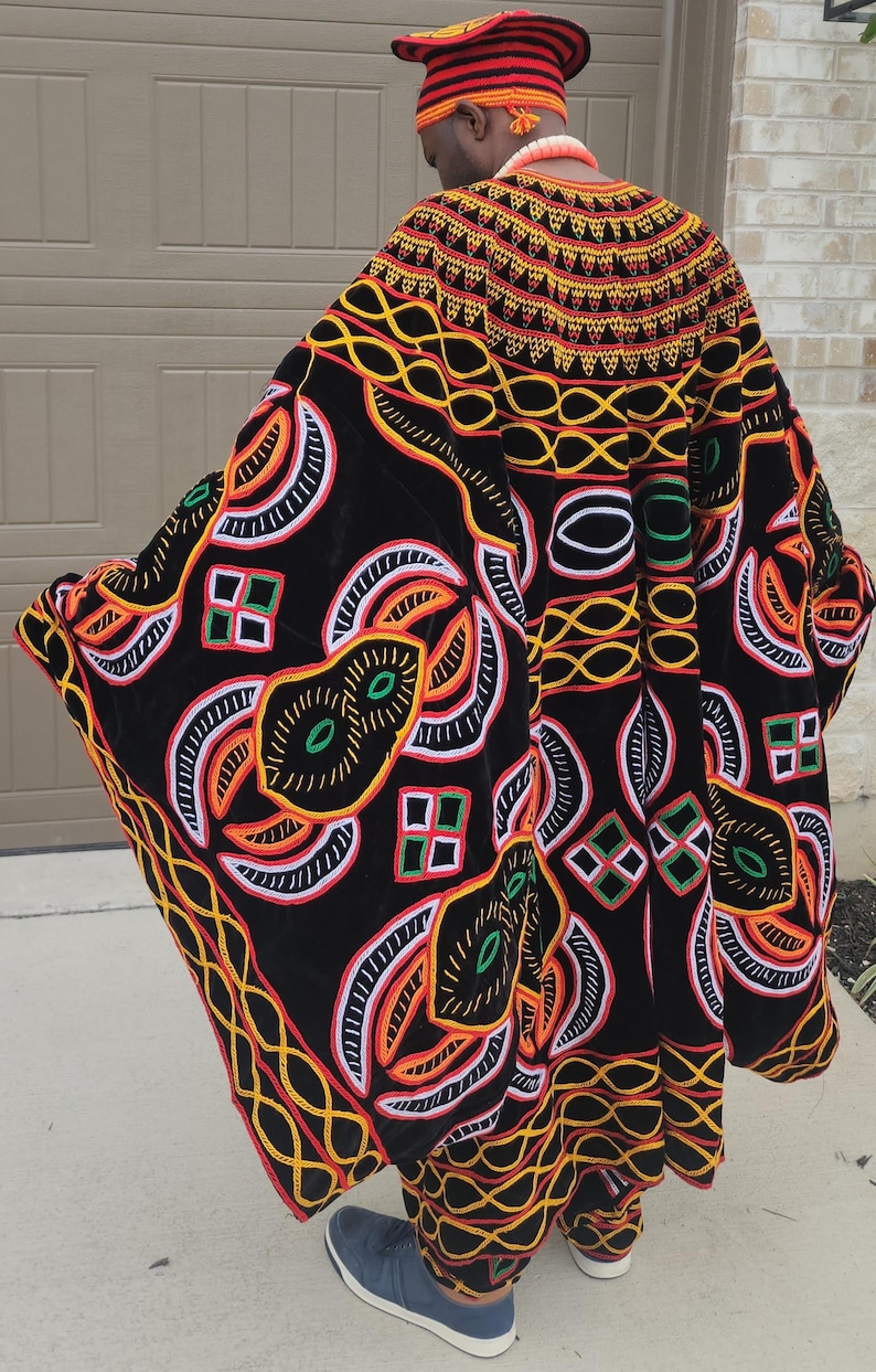 May include: A black, embroidered robe with vibrant patterns in orange, yellow, green, and white. The robe features intricate geometric and floral designs, and is part of a traditional cultural garment.