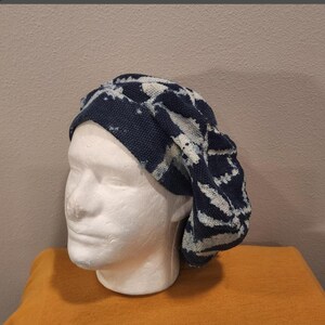 Puede incluir: Un gorro de punto con estampado azul oscuro y blanco. El gorro se exhibe en una cabeza de maniqu&iacute; blanca. El gorro tiene un aspecto suave y texturizado y un ajuste relajado. El gorro es probablemente hecho a mano y adecuado para climas fr&iacute;os.