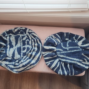 Puede incluir: Dos sombreros redondos de tela azul marino y blanca. Los sombreros tienen un aspecto texturizado con un dise&ntilde;o de l&iacute;neas blancas sobre un fondo azul marino. Los sombreros est&aacute;n colocados sobre una superficie rosa.