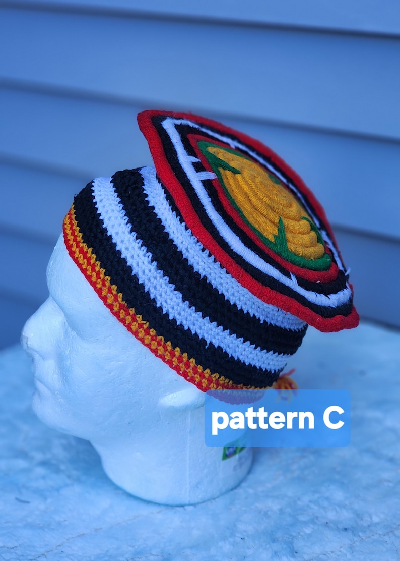May include: A handmade crochet hat with a unique design. The hat features black and white stripes, a red and yellow trim, and a decorative top with a yellow and green emblem. The text "pattern C" is visible.