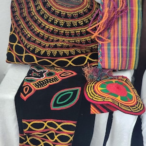 May include: An assortment of handmade textile items, including a black bag with intricate yellow, red, and green embroidery, a striped tote bag, and a hat with a colorful design. The items showcase vibrant colors and detailed craftsmanship.