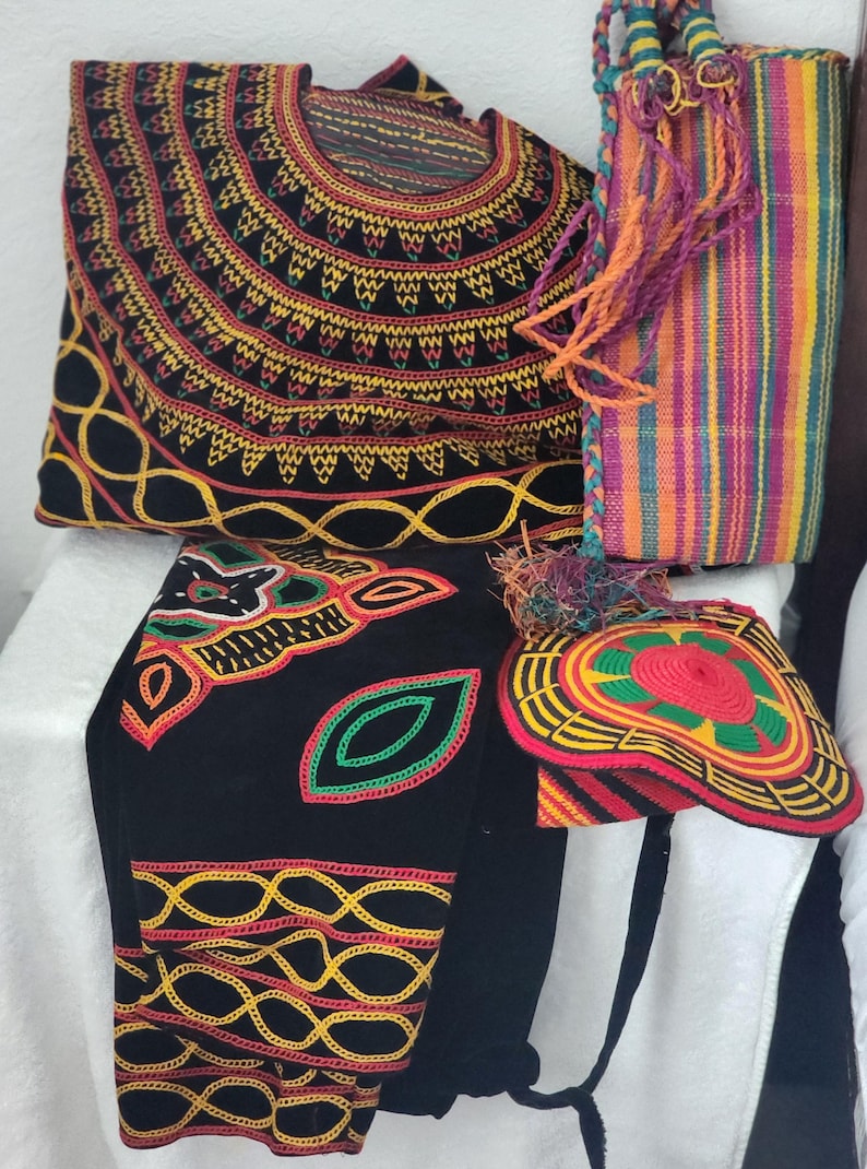 May include: An assortment of handmade textile items, including a black bag with intricate yellow, red, and green embroidery, a striped tote bag, and a hat with a colorful design. The items showcase vibrant colors and detailed craftsmanship.
