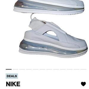 May include: Pair of white leather trainers with a distinctive design. The shoes feature a transparent, bubble-like sole and a strap detail. The trainers are a modern style, suitable for casual wear.