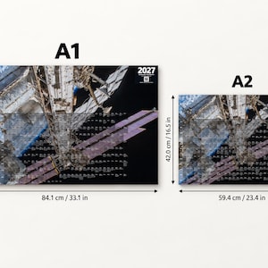 K&ouml;nnte beinhalten: Zwei rechteckige Wandkalender f&uuml;r 2027 mit einer Fotografie einer Raumstation. Das Format A1 misst 84,1 cm x 59,4 cm und das Format A2 misst 59,4 cm x 42,0 cm. Beide zeigen das Jahr 2027 und einen QR-Code.