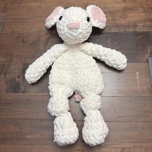 May include: A white crocheted stuffed animal shaped like a lamb with pink ears and a pink nose.