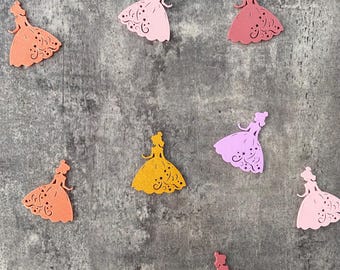 Può includere: Nove figure di principessa di carta ritagliate in vari colori, tra cui rosa, arancione, giallo e bianco. Le figure sono disposte in uno schema sparso su uno sfondo grigio testurizzato.