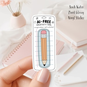 Pode incluir: Um adesivo de vinil brilhante à prova d'água de 7,6 cm de diâmetro, branco, com um lápis de desenho animado em uma folha de papel pautado. O adesivo diz "AI-FREE CREATIVITY TOOL imagination not included".