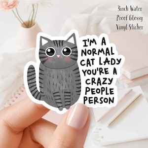 May include: A 3-inch water-proof glossy vinyl sticker featuring a cartoon gray cat with the text "I'm a normal cat lady you're a crazy people person."
