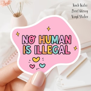 May include: A pink, die-cut vinyl sticker with the text "NO HUMAN IS ILLEGAL" in colorful bubble letters. The sticker is approximately 3 inches in size and features star and heart graphics. The sticker is water-proof and glossy.